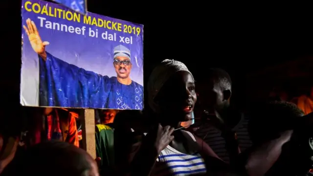 Un poster de Madické Niang porté par des adolescente lors d'un meeting tenue la nuit.