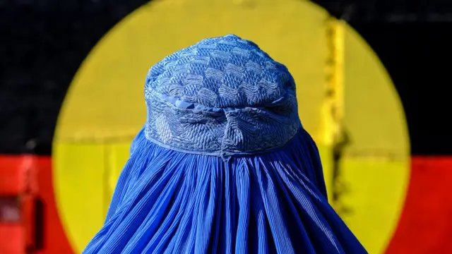 Burkalı kişi Aborjin bayrağının önünde