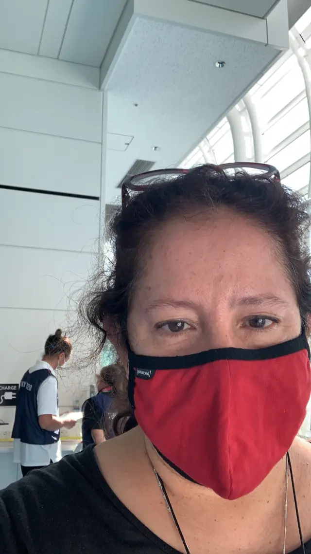 Lourdes arrives at the airport, wearing a mask