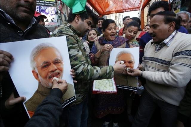 Indian people feed sweets to a poster of Indian Prime Minister Narendra Modi as they celebrate the Indian Air Force's air strike across the Line of Control (LoC) near the international border with Pakistan; in Jammu, the winter capital of Kashmir, India, 26 February
