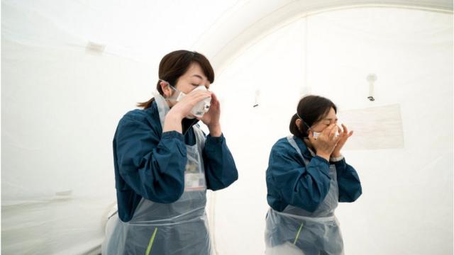 日本东京医务人员准备防护装备，准备对潜在的新冠病毒患者进行筛查。