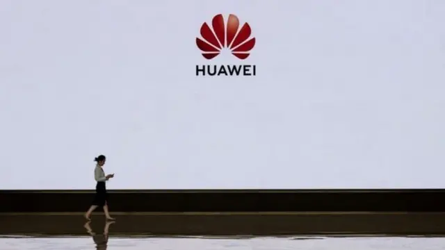 Mulher passa pela logo da Huawei