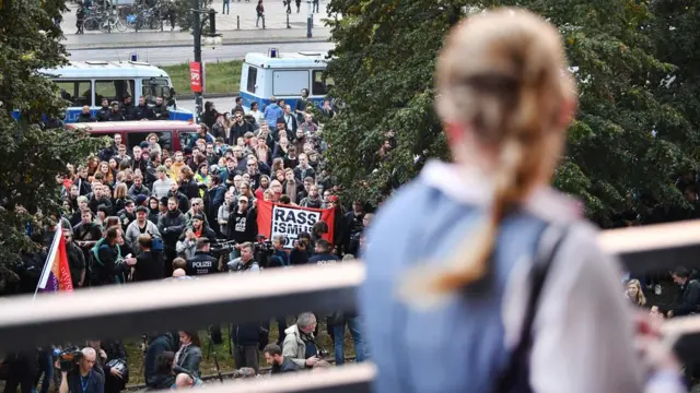 AfD destekçisi bir kadın, partilerini protesto eden kitleye bakarken. Dün akşam Almanya'da AfD'ye yönelik çeşitli protestolar gerçekleşti