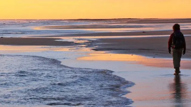 Mulher caminha na praia