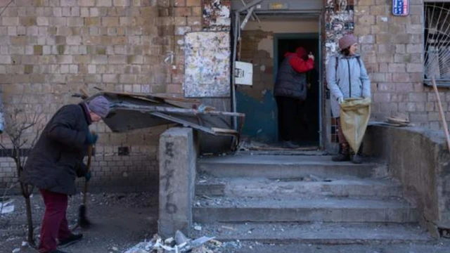 युद्धका कारण ध्वस्त भएका संरचनाबीच उभिएका युक्रेनीहरू।