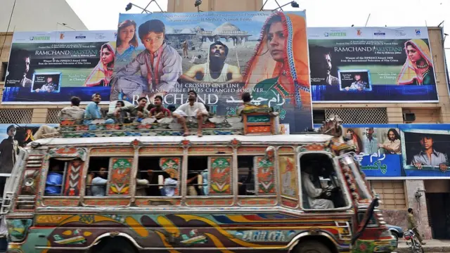 બોલીવૂડ ફિલ્મનું પોસ્ટર અને તેની સામેથી એક બસ પસાર થઈ રહી છે