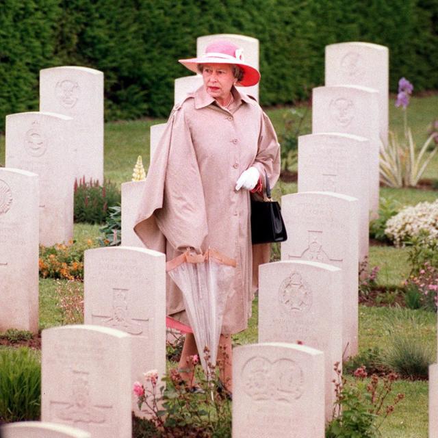 Rainha caminhando pelas lápides no Cemitério de Bayeux após uma cerimônia de comemoração do Dia D