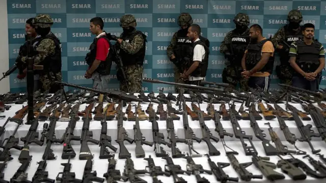 Efectivos de la Marina de México escoltan a 5 supuestos miembros del cartel de los Zetas, frente a una multitud de armas confiscadas