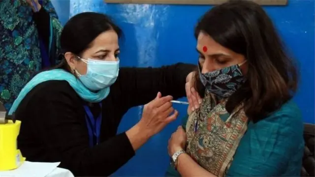 દિલ્હીમાં એક મહિલનાને રસી આપતાં આરોગ્યકર્મી