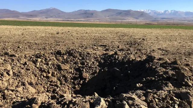 Воронка в поле от упавшего снаряда