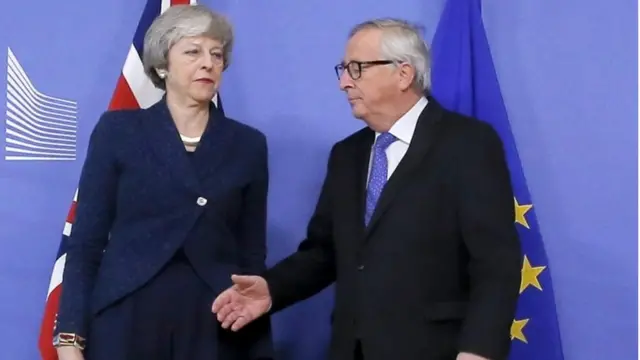 O presidente da União Europeia, Jean-Claude Juncker, com a mão estendida para Theresa May