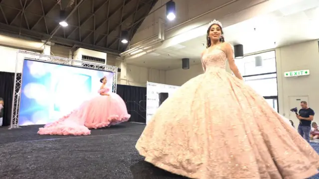 Dos jóvenes modelan vestidos de quinceañera en la feria que realiza la revista Quinceañera LA