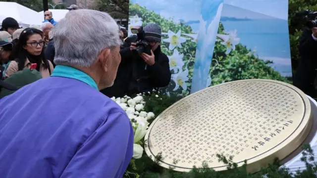 有受害者家属献完花后，仔细端详着二二八的纪念碑文