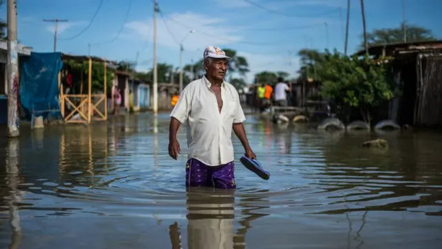 Hombre caminando por la calle con el agua pasando las rodillas.