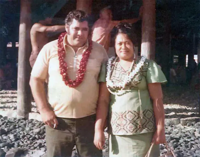 Os pais de Lance em 1974; um casa de polinésios com colares de flores em meio ao fundo praiano