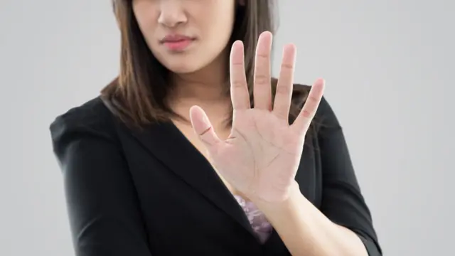 Mujer con la mano alzada en señal de rechazo.