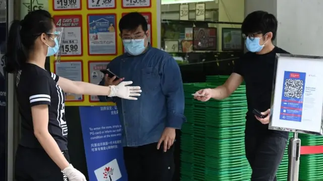 A man shows his ID card to a shop employee as he enters the store