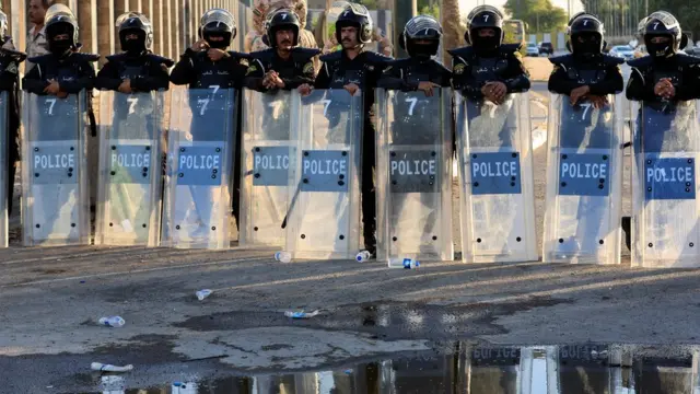 Police officers hold riot shields
