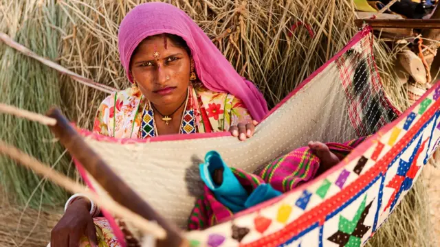 बच्चे को पालने में झुलाती हुई मां