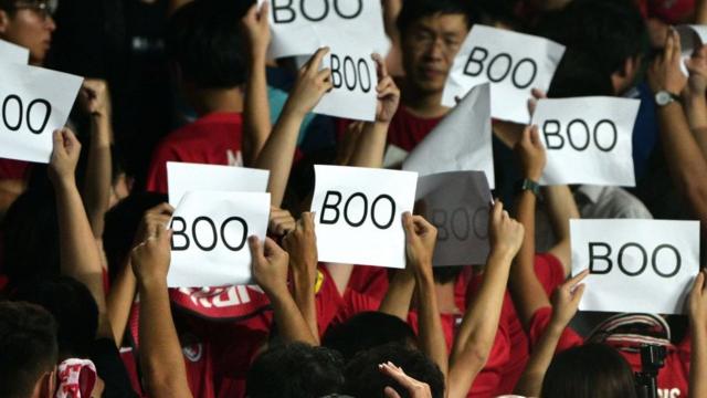 有一些觀眾則舉起印有「Boo」字樣的紙片，並在奏國歌時背向球場。