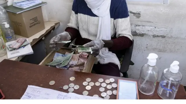 Un homme portant un masque en train de compter l'argent.