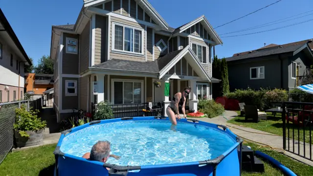 زوجان يحاولان معالجة الحر عن طريق الغطس في بركة بلاستيكية نصباها في منزلهما في فانكوفر. رجّحت الشرطة أن يكون الحرّ قد أدى إلى مقتل 69 شخصاً في فانكوفر، وسجلت عشرات الوفيات في مناطق أخرى.