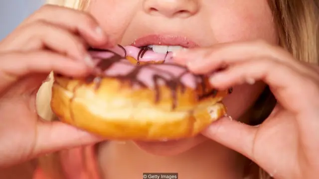 Primer plano de mujer comiéndose un donuts.