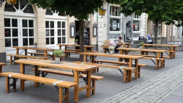 জার্মানিতে লকডাউন শিথিল করার পর একটি রেস্তোরাঁর বাইরে একজন নারী বসে আছেন।