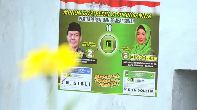 Stiker bergambar wajah Eha yang berdampingan dengan caleg tandemnya, Haji Sibli, yang berlaga di tingkat provinsi. Sibli merupakan donatur kampanye Eha yang maju tanpa modal.