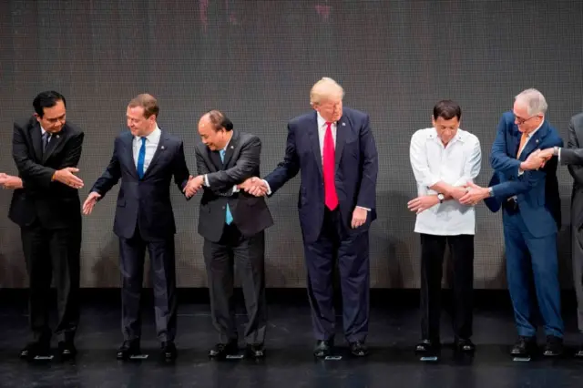 O ex-presidente dos Estados Unidos Donald Trump e outros líderes cruzando as mãos