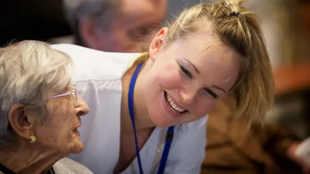 Una enfermera cuida de una anciana en un asilo.