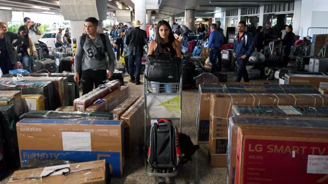 Em terminal, médicos cubanos carregam malas e pacotes de viagem