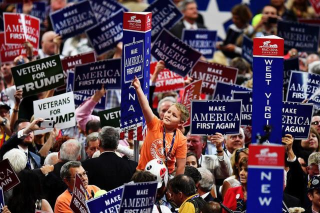 Trump supporters hold up signs that read "Make America First Again" during the Republican National Convention on July 20, 2016