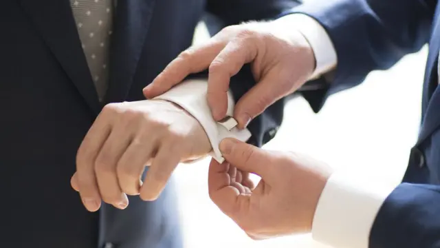 Мужчина помогает другому застегнуть запонки