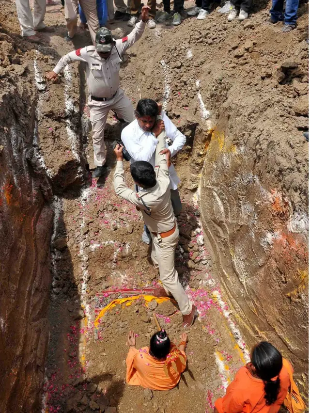 A devotee of Indian Hindu Akhara leader Trikal Bhawanta grapples with two police officials in a deep grave, alongside the seated Trikal Bhawanta, as she undergoes a "burial ritual" on 26 April 2016