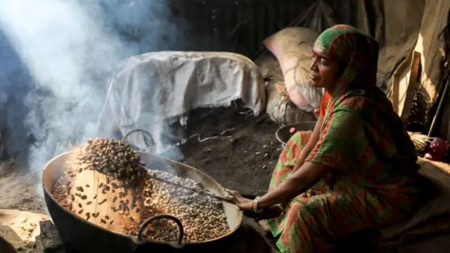 বাড়িতে চীনা বাদাম ভাঁজছেন বাংলাদেশি এক নারী। একজন নারীকে পরিবারে গড়ে এ ধরণের ১২টি ‘অবৈতনিক‘ কাজ করতে হয়, যেখানে পুরুষকে করতে হয় তিনটিরও কম।