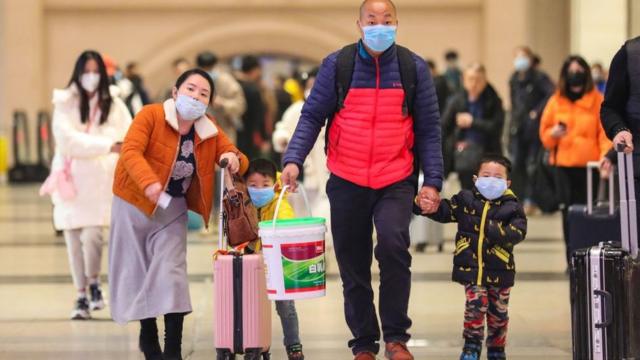 Família com máscaras e malas caminha em estação