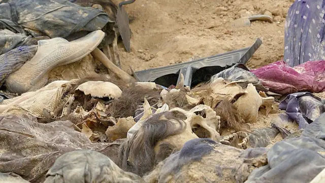 A forensic scientist inspects human remains in the al-Samawa desert on April 25, 2005 in Muthanna province, 270km south of Baghdad, Iraq. Skulls and bones, clothing and other belongings found in shallow graves here offer up valuable clues to investigators gathering evidence against Saddam Hussein and others from the former regime.