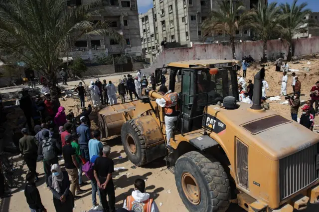 Buldožer i ljudi na mestu ekshumacije u bolnici Naser