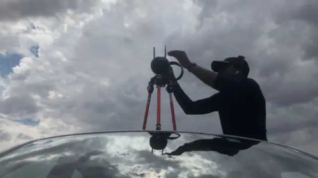 Tawanda fixe son appareil photo sur le toit d'une voiture.