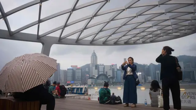 Khách du lịch chụp ảnh Cảng Victoria ở Hong Kong.