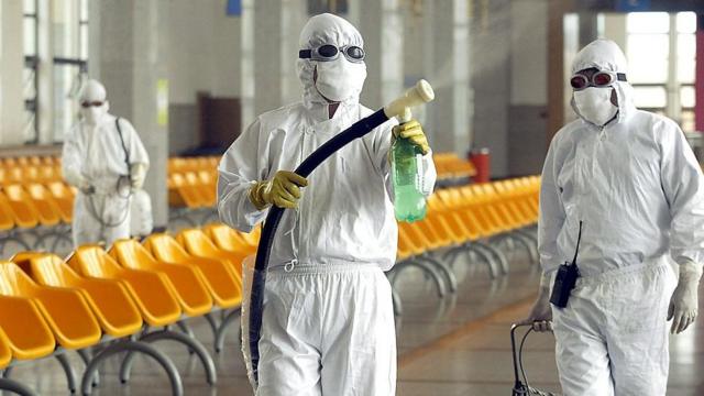 Dos trabajadores limpian la estación de tren de Pekín en pleno brote del SARS en China, en 2003.
