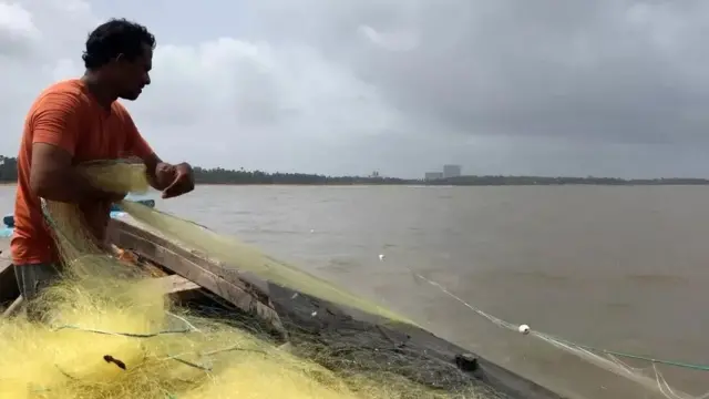 मछली पकड़ने के लिए जाल डालता एक व्यक्ति