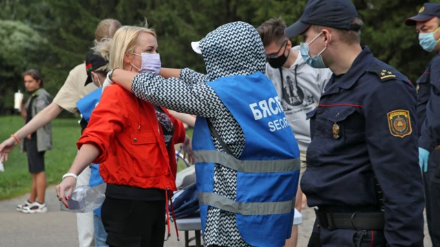 Женщину досматривают на митинге Светланы Тихановской