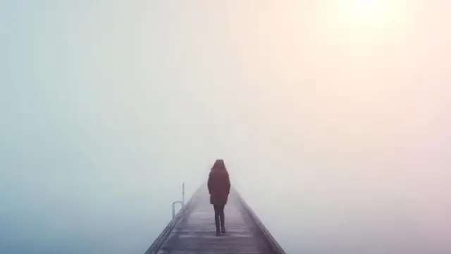 فتاة تقف بمفردها فوق جسر يطل على أحد البحار