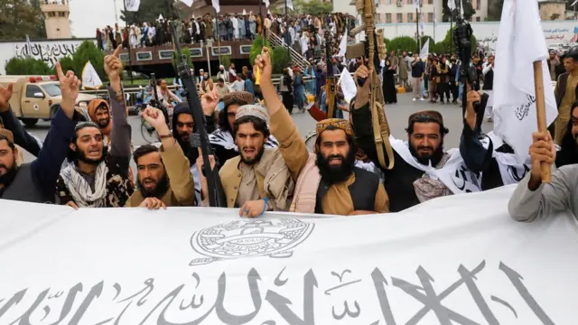 Taliban fighters hold an Islamic Emirate of Afghanistan flag on the first anniversary of the fall of Kabul on a street in Kabul, Afghanistan, on 15 August 2022