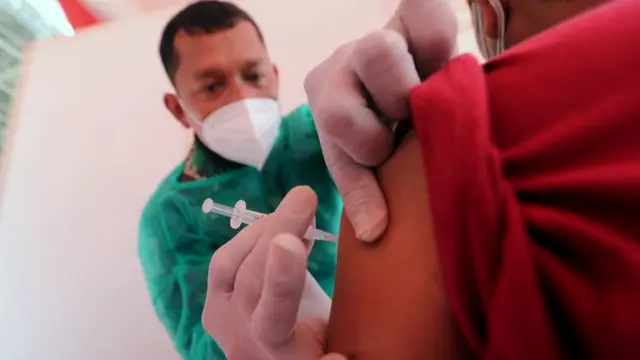 2021年6月26日，一名印尼軍醫在雅加達進行的新冠疫苗接種推廣活動中為一名男士注射由Biofarma公司生產的科興疫苗。