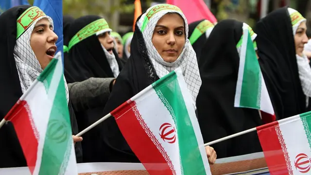 Female members of Iran's paramilitary Basij militia wave national flags.