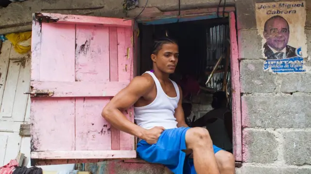 Otro familiar de las hermanas Wilianny Robles, de ocho años, y Fabianny Robles, de diez años, que murieron en el sector El Túnel, del barrio de Capotillo, permanece inmóvil en una ventana tras el paso del huracán.