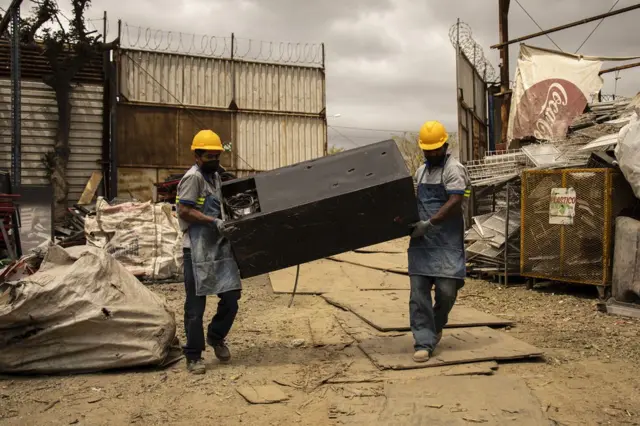 Trabalhadores carregam uma geladeira velha nos arredores da Cidade da Guatemala